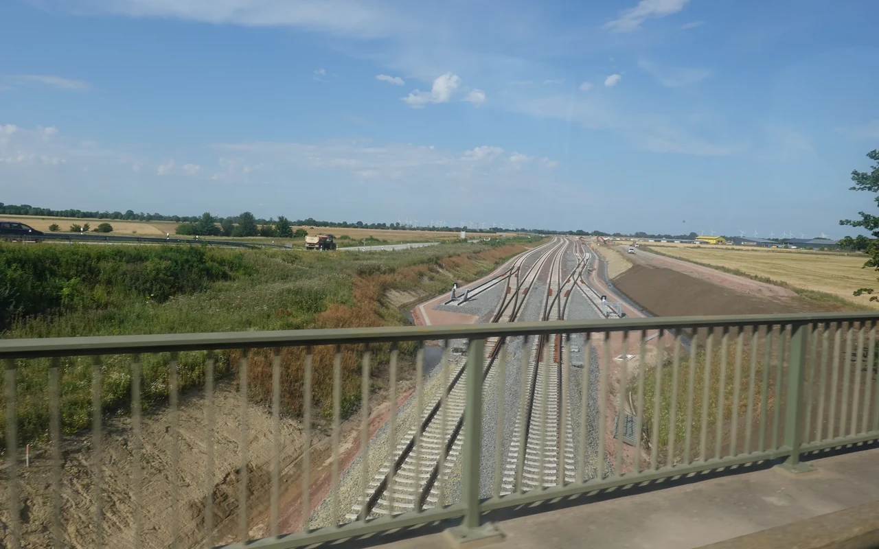 New railway tracks near Burg auf Fehmarn, seen from a bridge with its railing in the foreground.