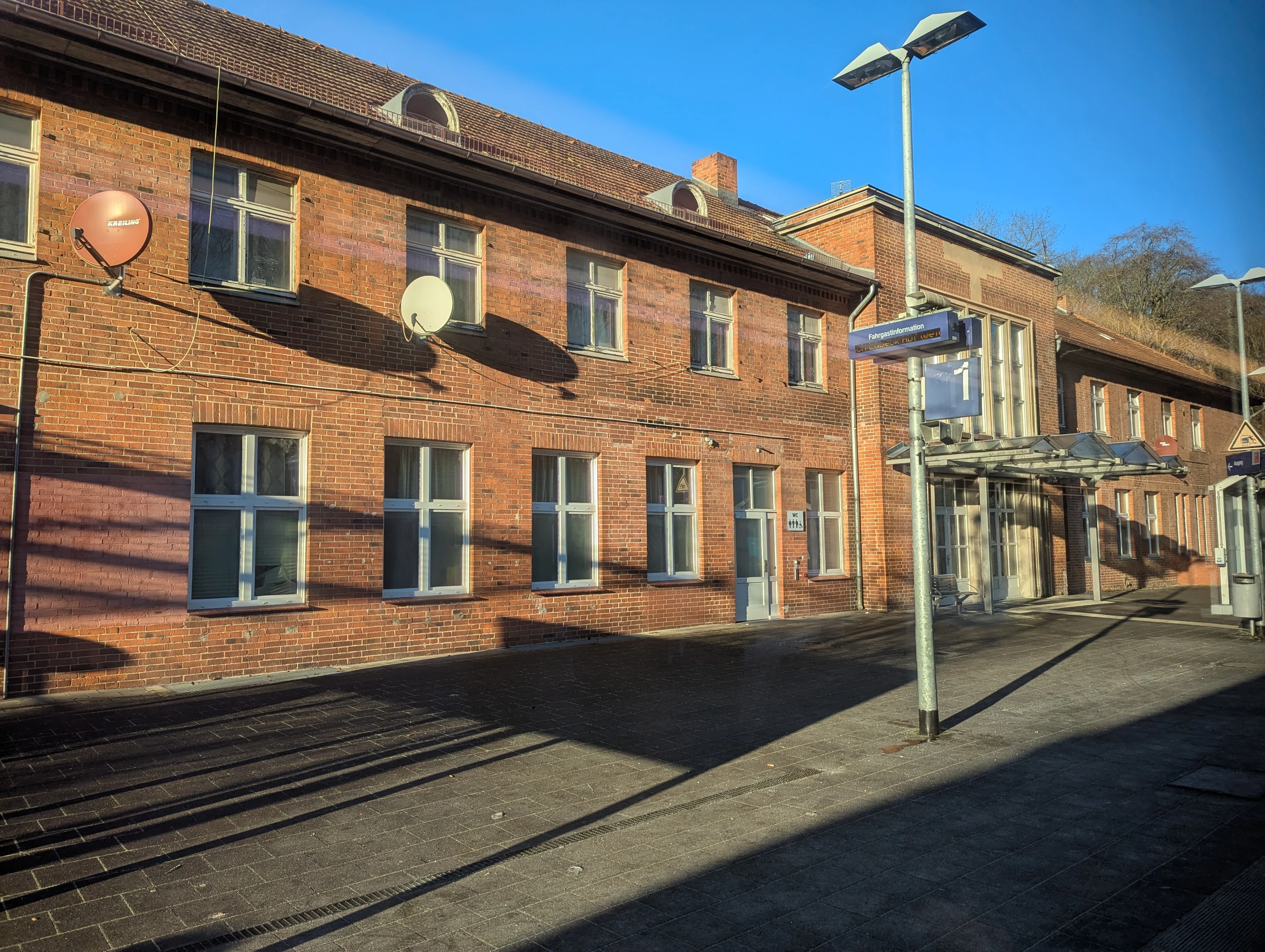 Brick station building at Bad Schwartau, viewed from the platform in winter sunlight.